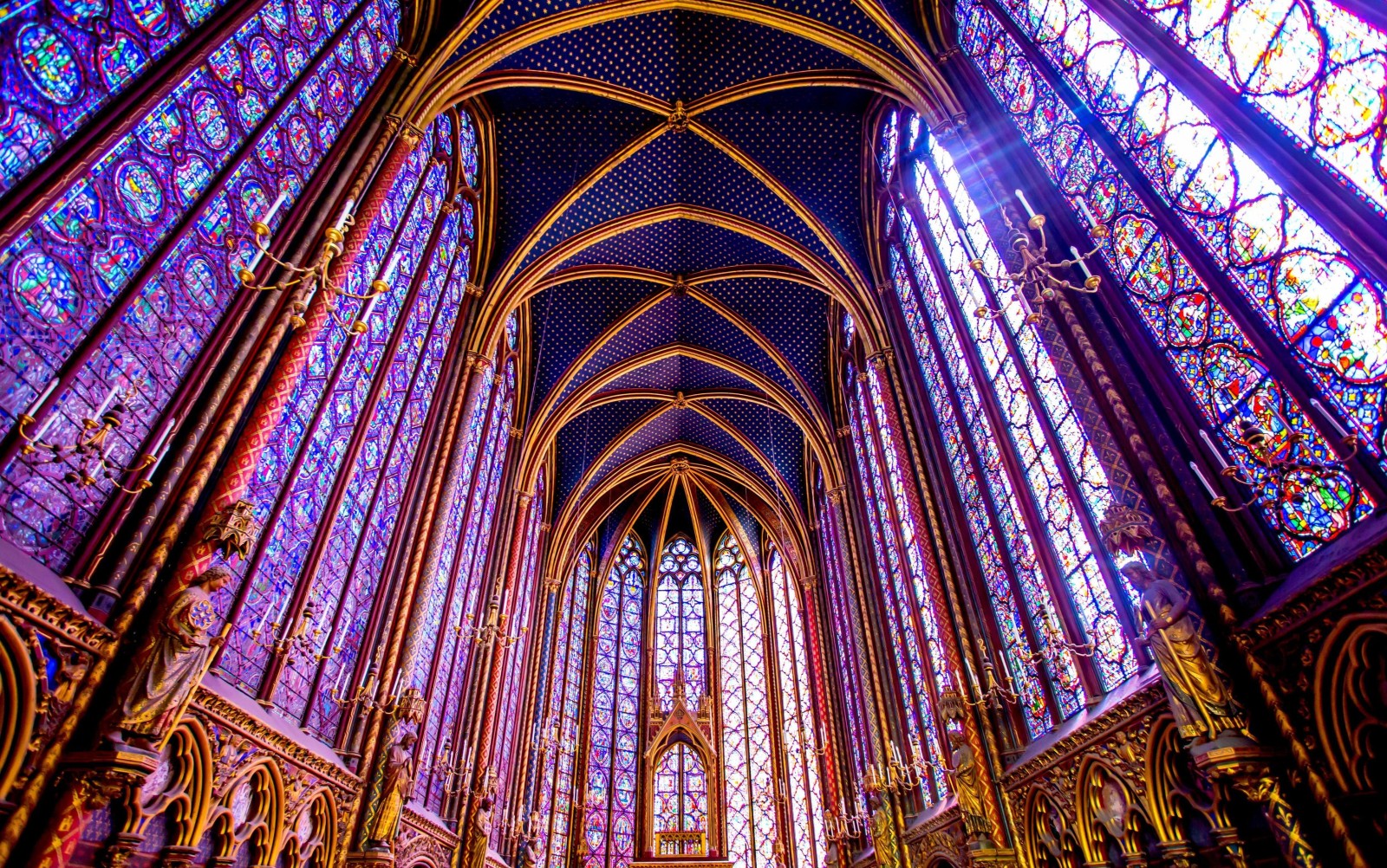 La lumière traverse les vitraux flamboyants de la chapelle gothique de la Sainte Chapelle à Paris.